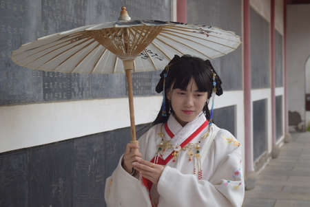 A young woman in traditional attire is holding an umbrella.の写真素材