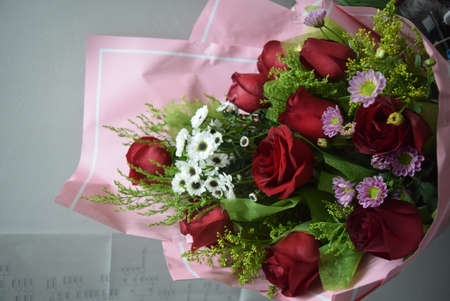 Bouquet of red roses and daisies on a pink background.の写真素材