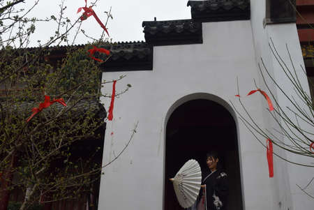 Chinese woman in traditional clothes holding a white umbrella in a temple.の写真素材