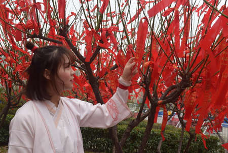 A girl in a white robe with a red flower in the gardenの写真素材