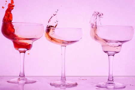 Colored cocktails with splash on purple background. Frontal view