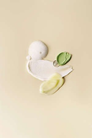 Different cosmetic smears on a light beige background. View from above.