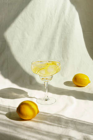 Summer cocktail with lemons and sun shadow. On the background of linen fabric. Front view.の写真素材