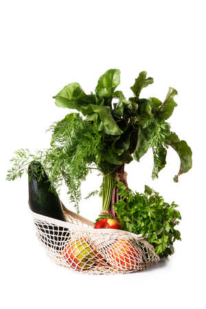 Green vegetables and fruits in a cotton string bag isolated on a white background. Front view. Environmental concept, no plastic.の写真素材