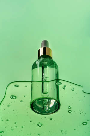 Cosmetic transparent bottle dropper container on a green background with gel liquid. Upwards view.の写真素材