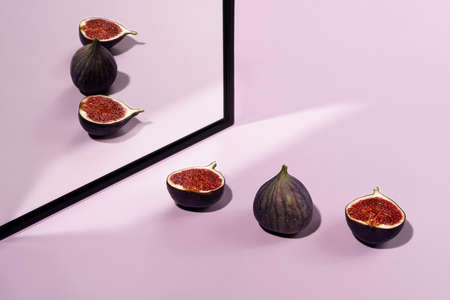 Figs with reflection in the mirror on a pastel pink background. Frontal view.の写真素材