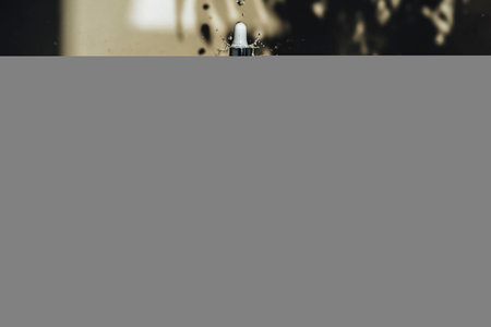 Cosmetic bottles standing on the stone. On a beige background with water drops and leaves shadows.の写真素材