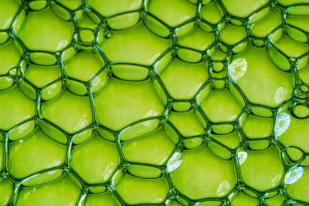 Neon green oil or serum background with bubbles. Top view