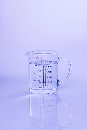 Water in a measuring container on a light blue background. Front viewの写真素材