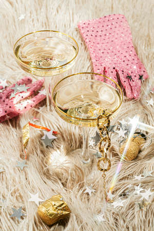 Two glasses of champagne on a pink faux fur rug and confetti scattered on the sides. Concept after party, new year or holiday.の写真素材