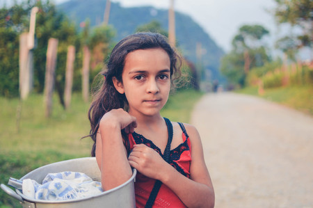 Pena Blanca, Honduras - May 6, 2015: Local girl carries a pot with tortillas to sell in the evening hours in a small village of coffee growers in Santa Barbara National Park. Hondurasのeditorial素材