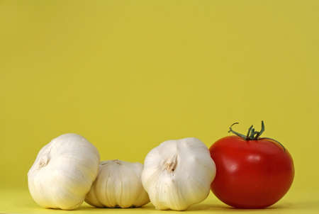 three garlic bulbs and a tomatoの写真素材