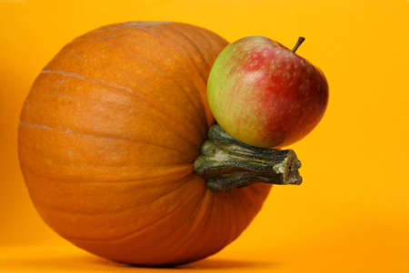 fresh whole pumpkin and apple on orange backgroundの写真素材