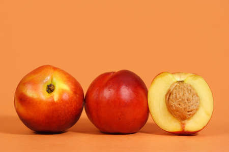 three nectarines with peach backgroundの写真素材