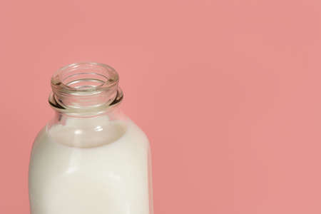 closeup on a glass bottle full of milk, on pink backgroundの写真素材