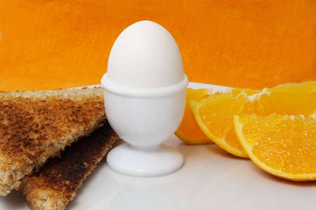 boiled egg, orange and bread as breakfastの写真素材
