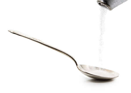 pouring sugar in a silver spoon, isolated on whiteの写真素材