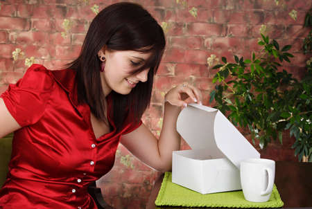 young woman looking in a white pastry box