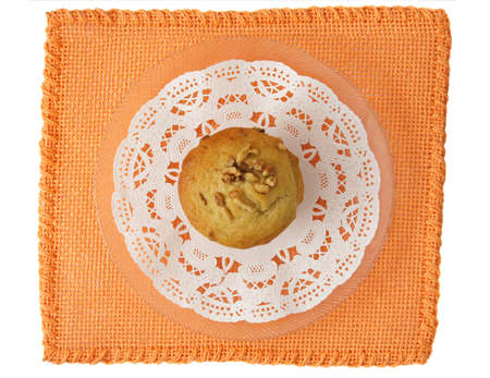 muffin with nut on white decorative paper over an orange tablecloth