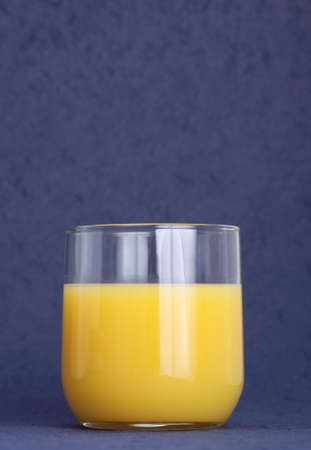small glass of orange juice, blue backgroundの写真素材