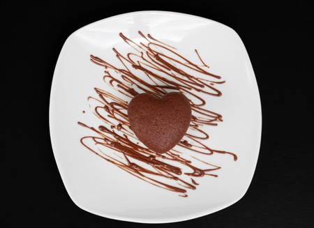 small chocolate cake in white plate, heart shapeの写真素材