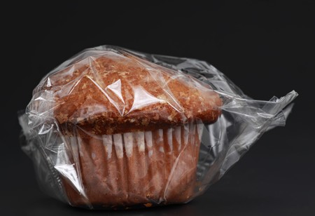 wrapped muffin isolated on black backgroundの写真素材