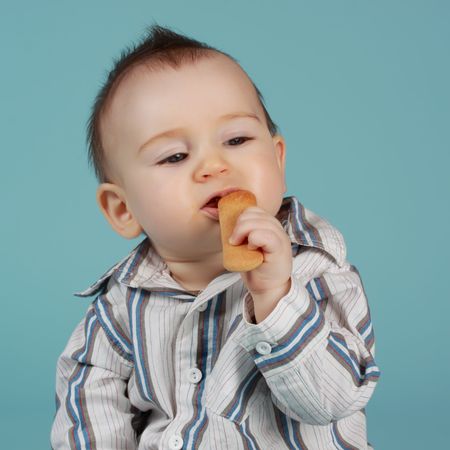 adorable 8 months cacasian baby boy eating a cookieの写真素材