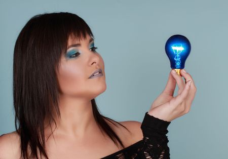 young woman holding a blue lightbulbの写真素材