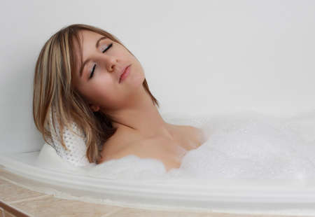 young caucasian woman relaxing in her bath with foam bubble