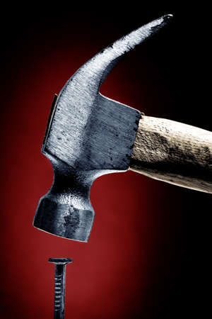 closeup on nail and hammer, red backgroundの写真素材