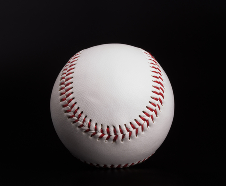 One new white baseball ball with red thread isolated on black backgroundの写真素材