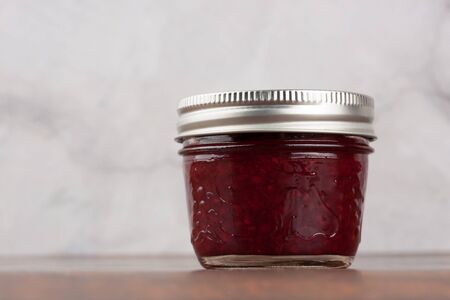 Delicious homemade raspberry jam in a reusable glass jarの写真素材