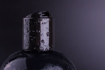 Big black hair shampoo bottle on black background