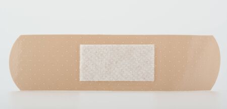 Close-up on a sticky beige plaster to protect wound, isolated on whiteの写真素材