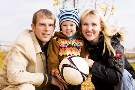 happy smiling family with a football ball outdoorの写真素材