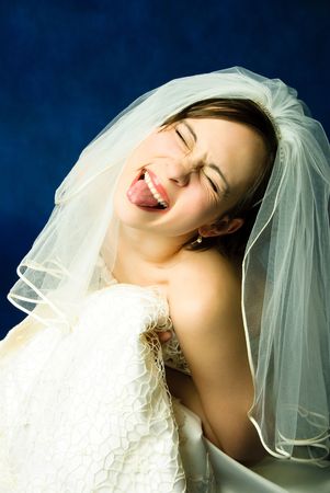 studio portrait of a young bride showing her tongue against red backgroundの写真素材