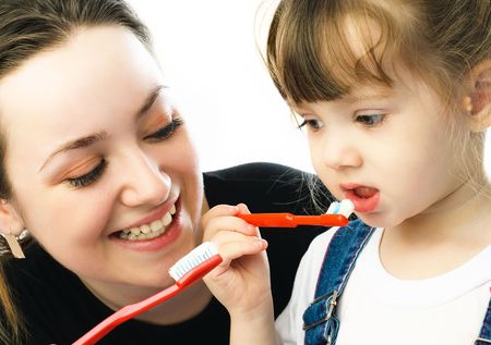 young beautiful mother teaching her daughter brushing teethの写真素材