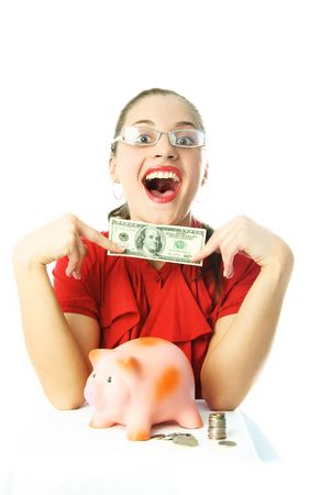 happy excited young woman putting money into her piggy bankの写真素材