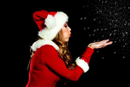 sexy young woman dressed as Santa blowing on the snowの写真素材