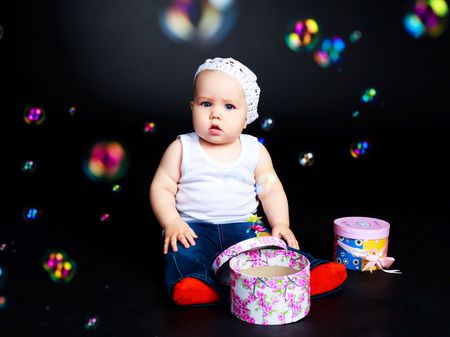 studio portrait of a cute baby with presents and soap bubblesの写真素材