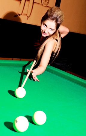 beautiful young blond woman playing billiard in the bar