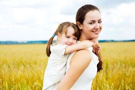 beautiful young mother and her daughter at the wheat field on a sunny dayの写真素材