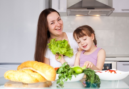 young mother and her five year old daughter cook together on the kitchen at homeの写真素材