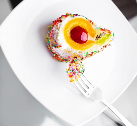cake with fruit and a fork on the white plateの写真素材