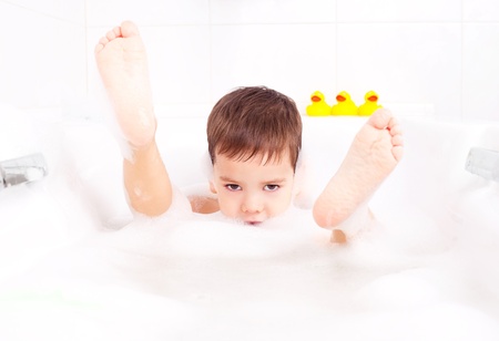 cute four year old boy taking a relaxing bath with foamの写真素材