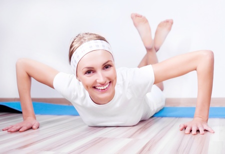 beautiful young blond woman working out on the mat at homeの写真素材