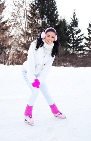 happy beautiful girl wearing warm winter clothes ice skatingの写真素材