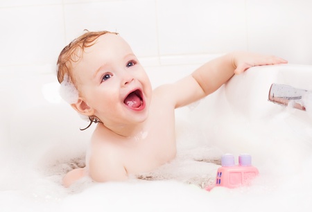 cute one year old boy taking a relaxing bath with foamの写真素材