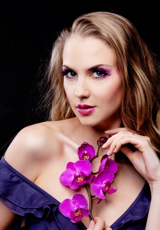 beautiful young woman with luxurious long curly hair and an orchidの写真素材