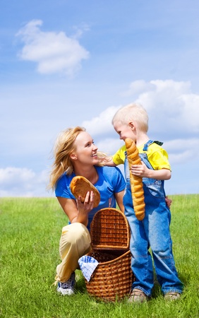 happy young  woman and her son having a picnic outdoor on a summer day (focus on the woman)の写真素材